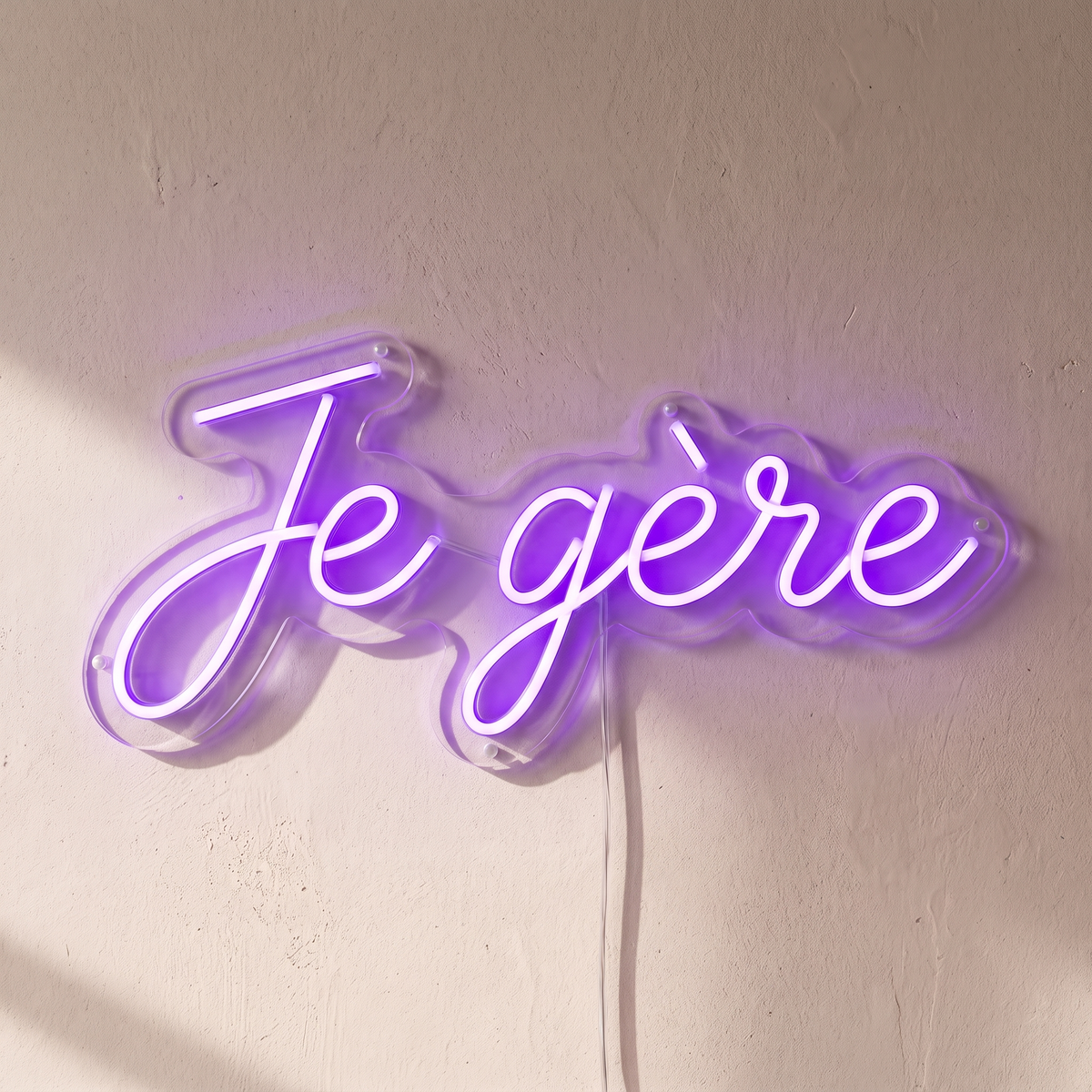 Gros plan du néon mural « Je gère » sur fond beige, tube allumé