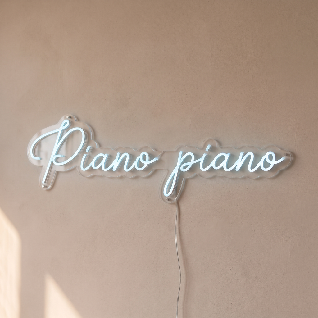 Gros plan du néon mural « Piano piano » sur fond beige, tube allumé