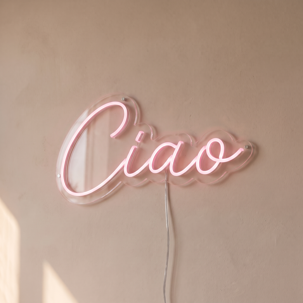 Gros plan du néon mural « Ciao » sur fond beige, tube allumé