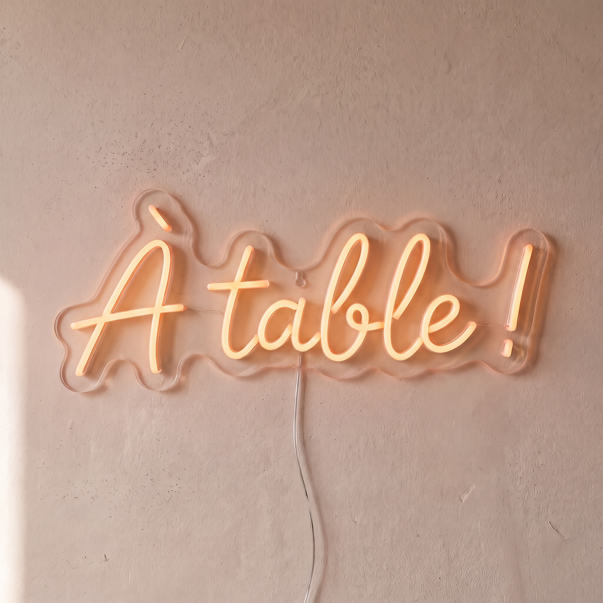 Néon mural « À table ! » blanc chaud, gros plan sur fond beige