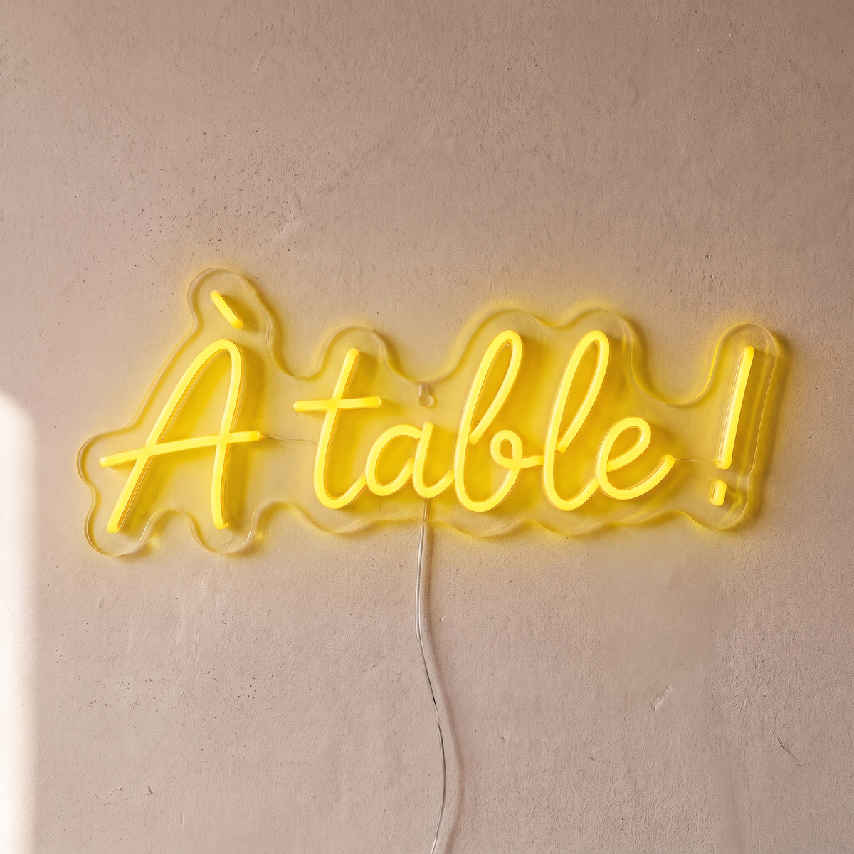 Néon mural « À table ! » jaune, gros plan sur fond beige