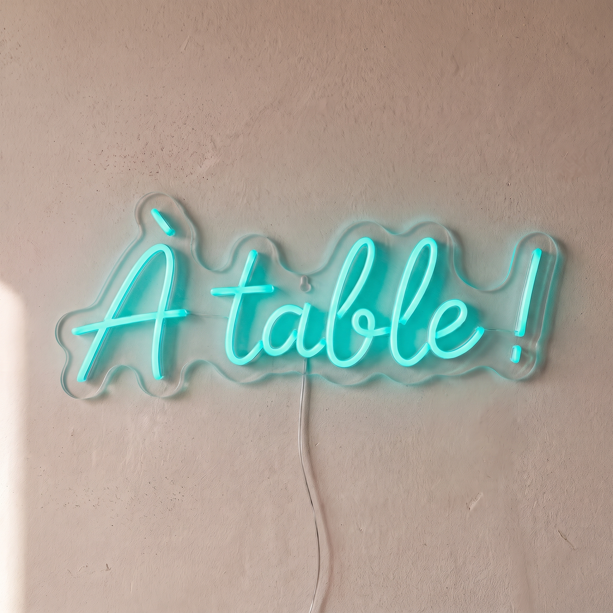 Néon mural « À table ! » turquoise, gros plan sur fond beige