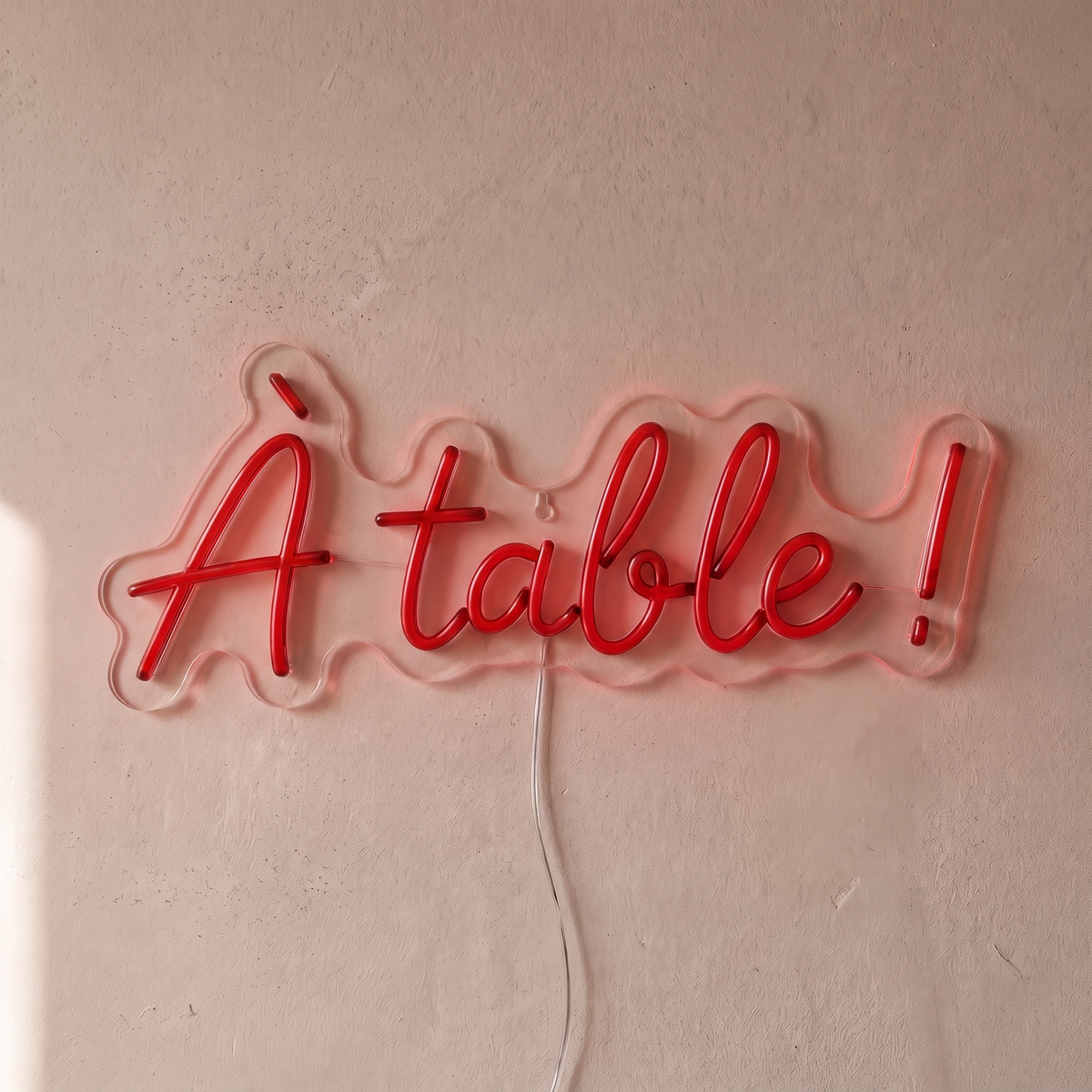 Néon mural « À table ! » rouge, gros plan sur fond beige