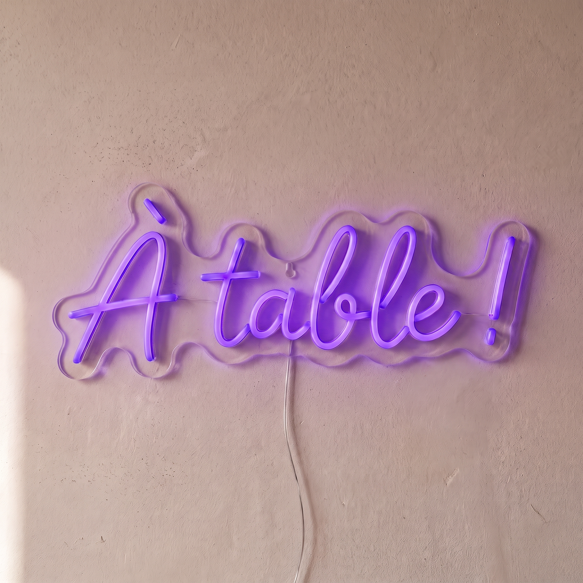 Néon mural « À table ! » violet, gros plan sur fond beige