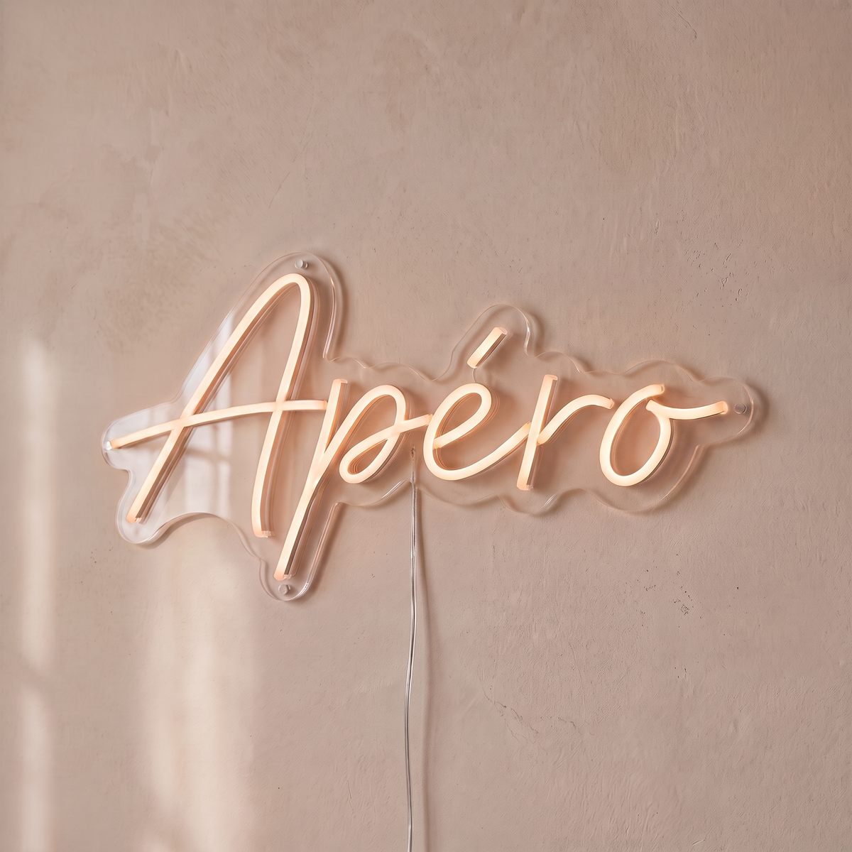 Néon mural « Apéro » rose pâle, gros plan sur fond beige