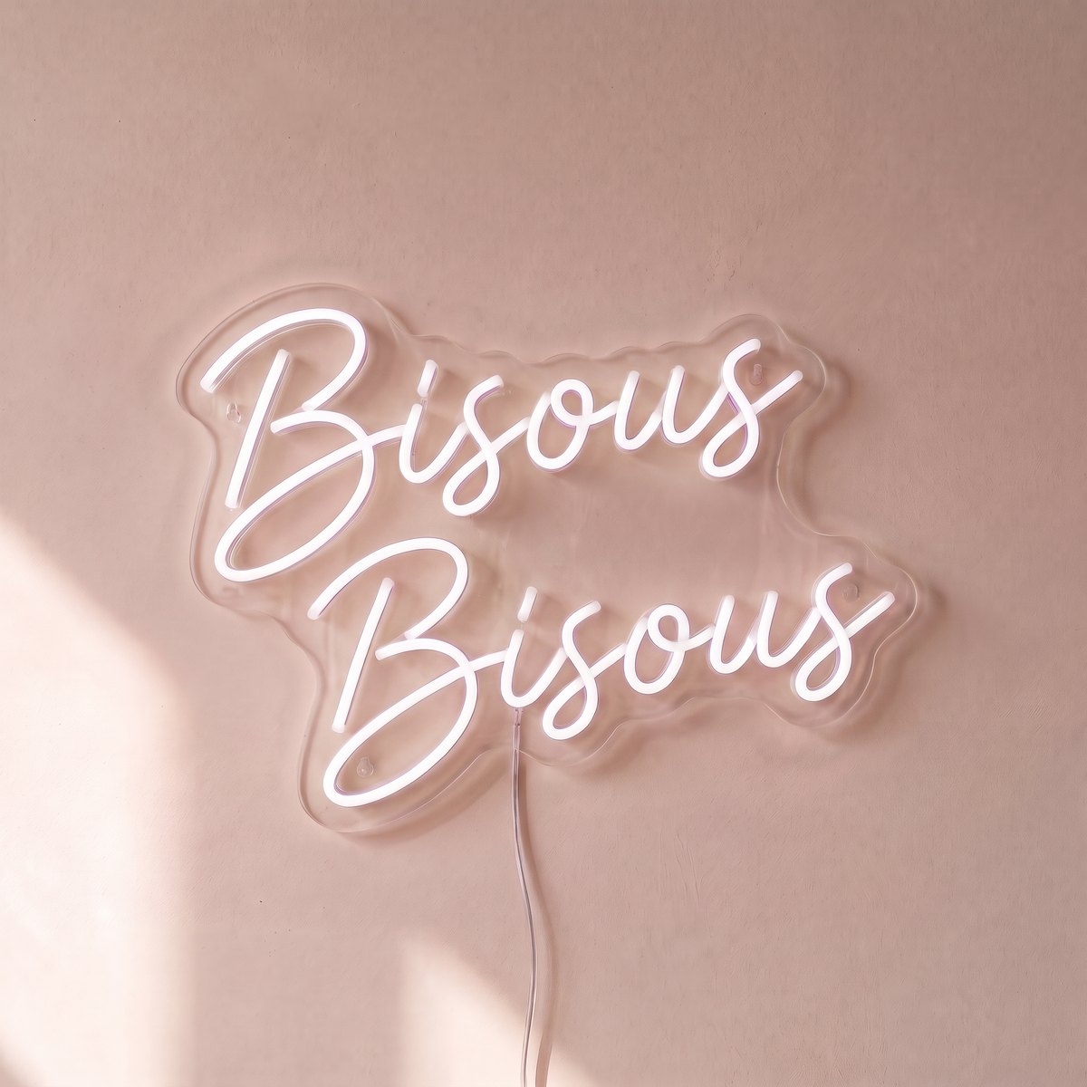 Néon mural « Bisous Bisous » blanc, gros plan sur fond beige