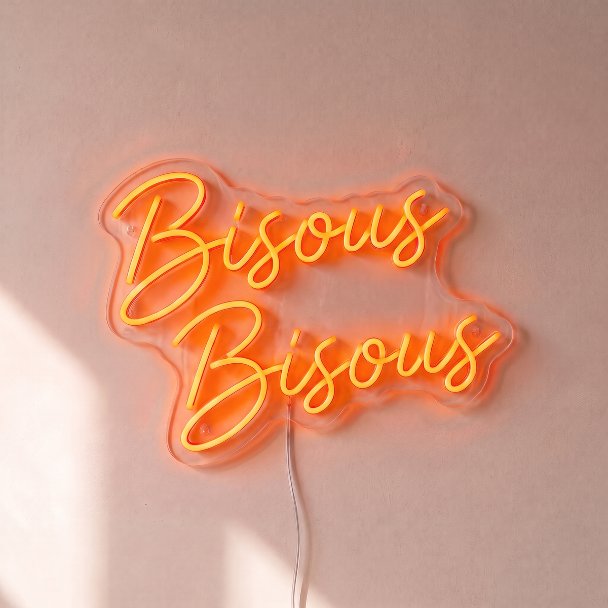 Néon mural « Bisous Bisous » orange, gros plan sur fond beige