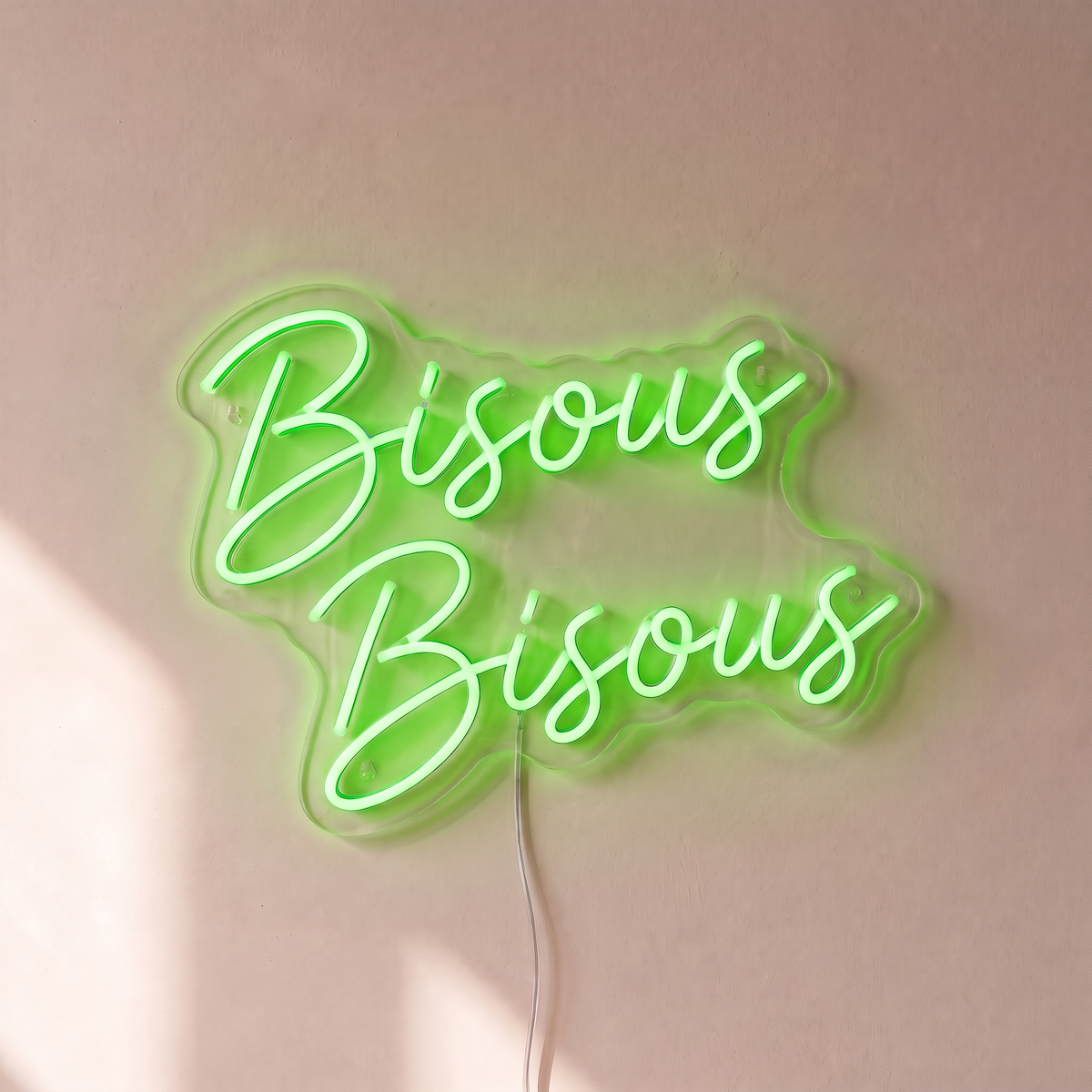 Néon mural « Bisous Bisous » vert, gros plan sur fond beige