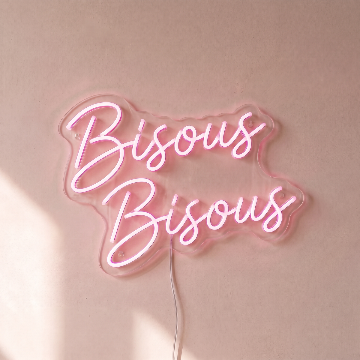 Néon mural « Bisous Bisous » rose pâle, gros plan sur fond beige