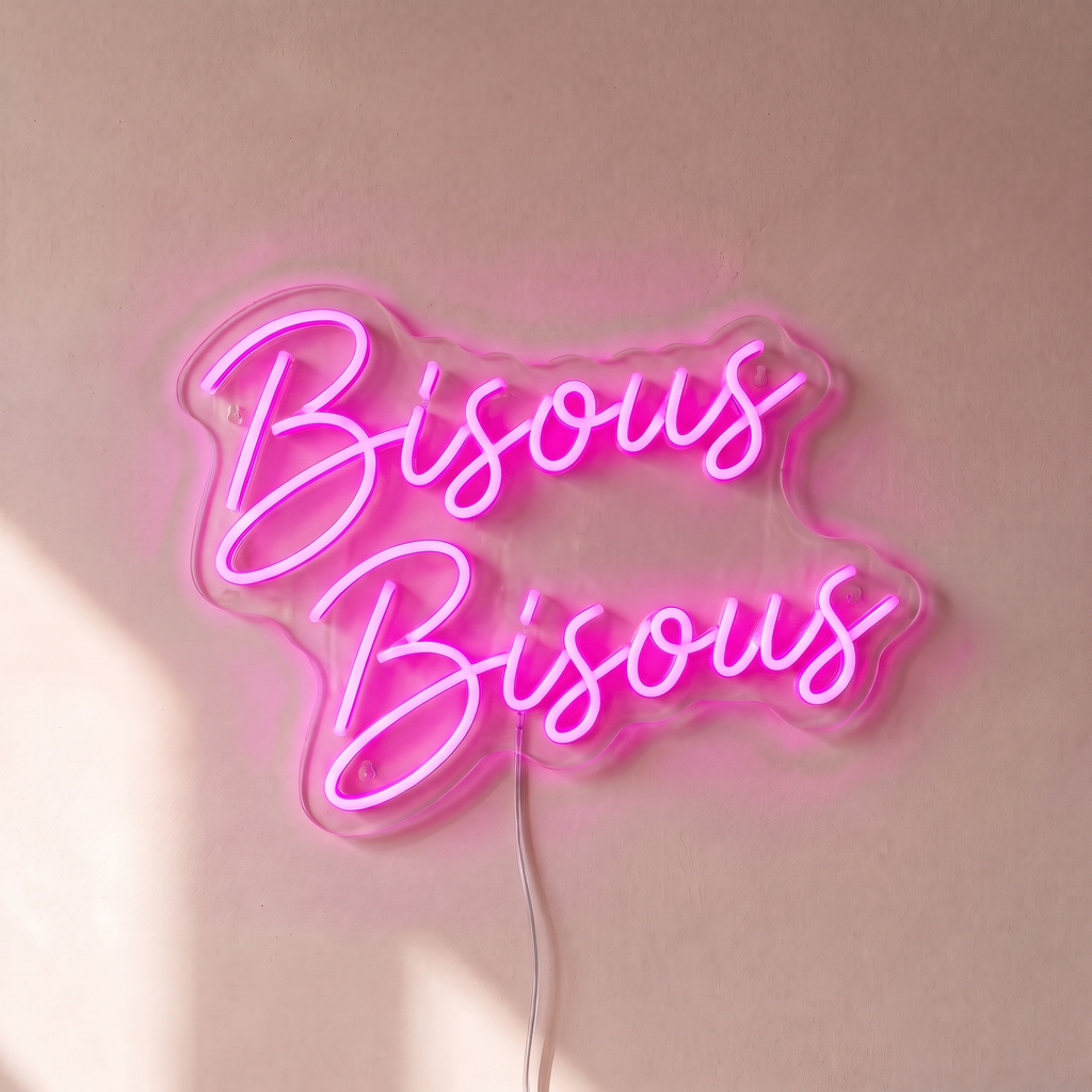 Néon mural « Bisous Bisous » rose, gros plan sur fond beige