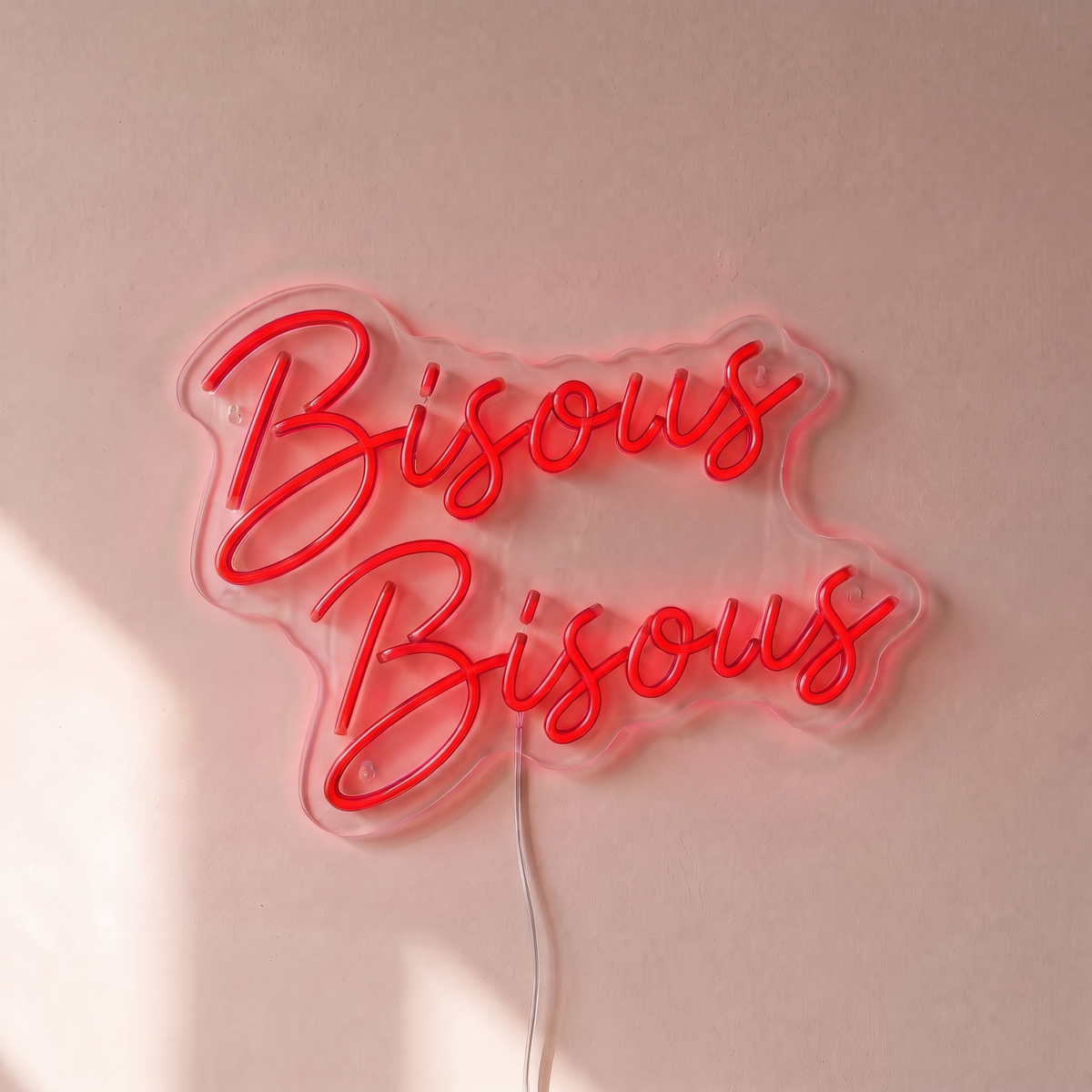 Néon mural « Bisous Bisous » rouge, gros plan sur fond beige