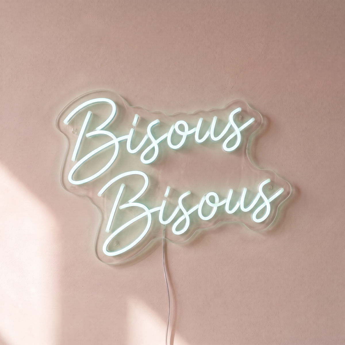 Néon mural « Bisous Bisous » blanc froid, gros plan sur fond beige