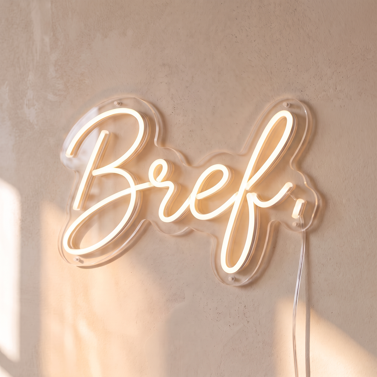Néon mural « Bref. » blanc chaud, gros plan sur fond beige