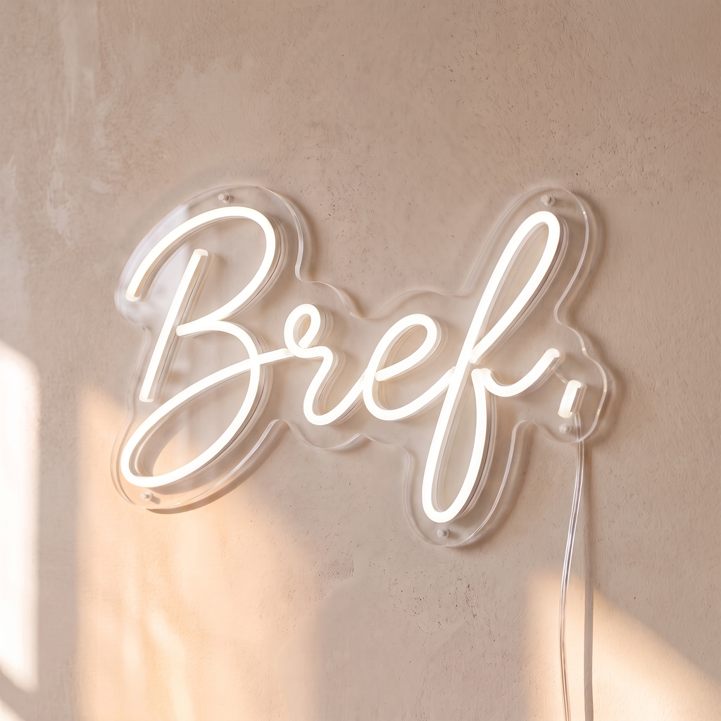 Néon mural « Bref. » blanc, gros plan sur fond beige
