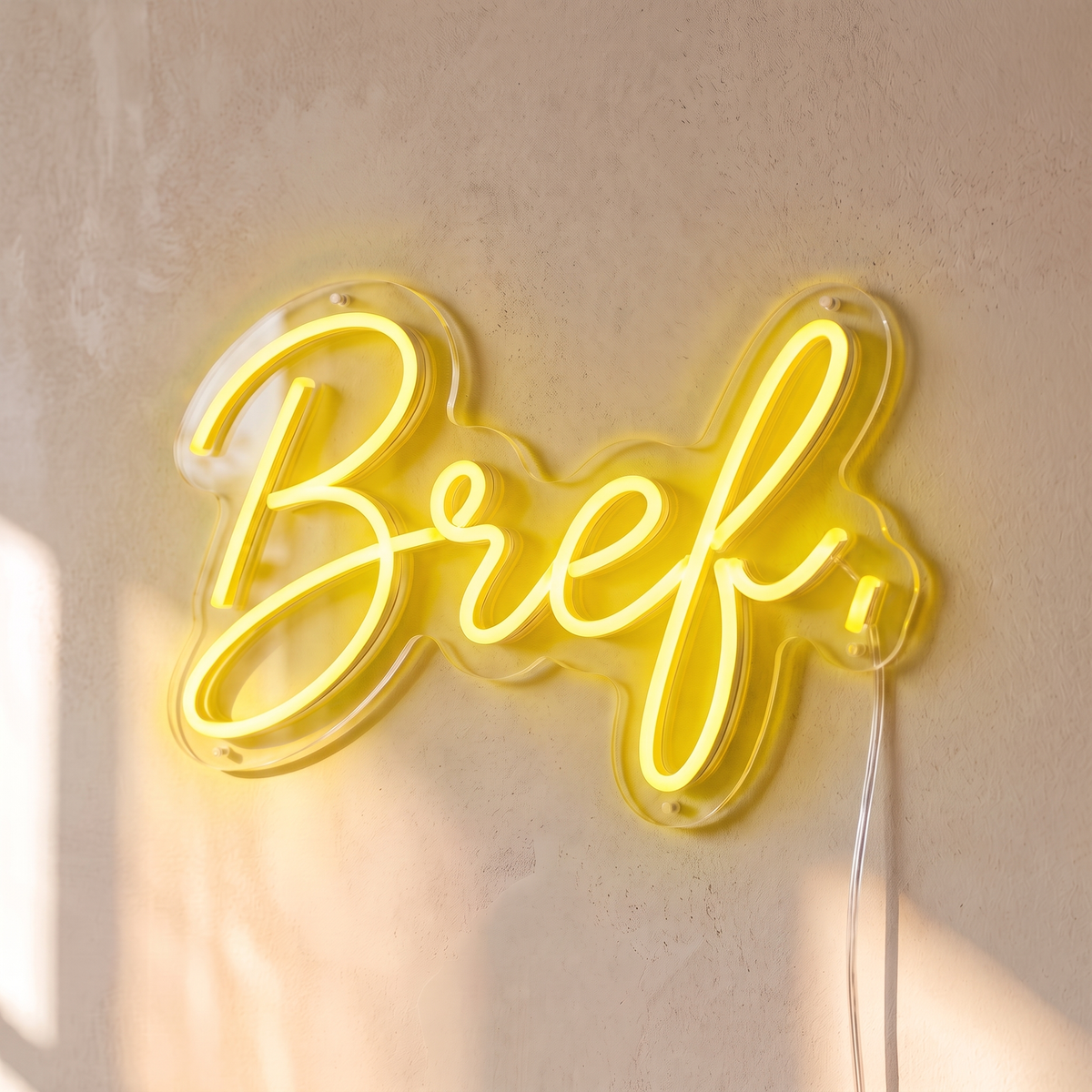 Néon mural « Bref. » jaune, gros plan sur fond beige