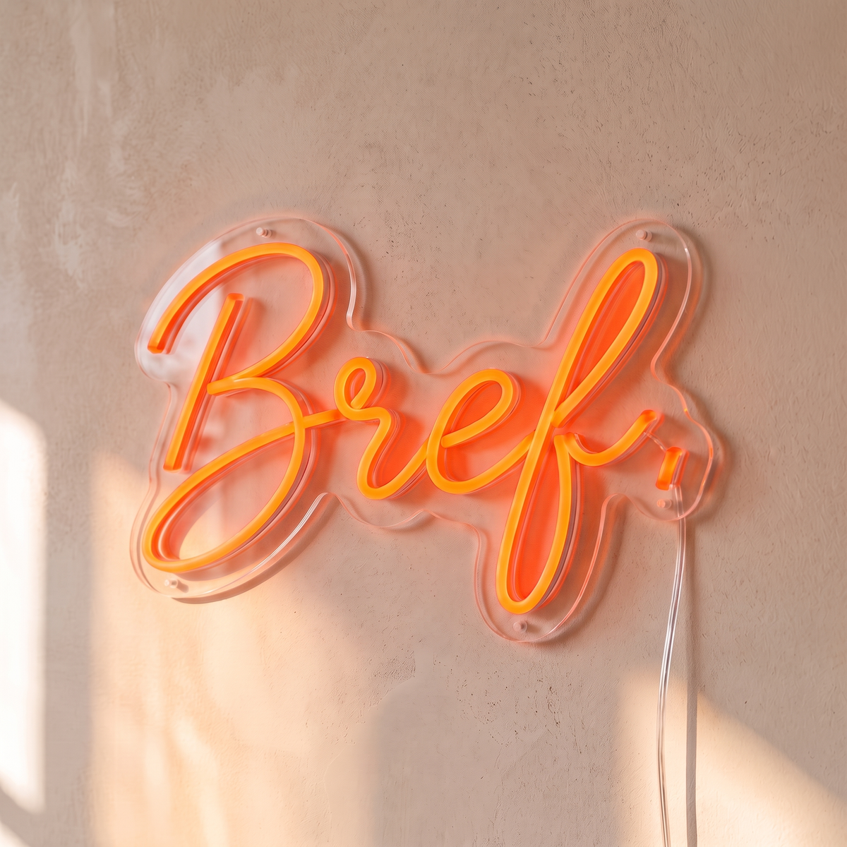 Néon mural « Bref. » rouge orangé, gros plan sur fond beige