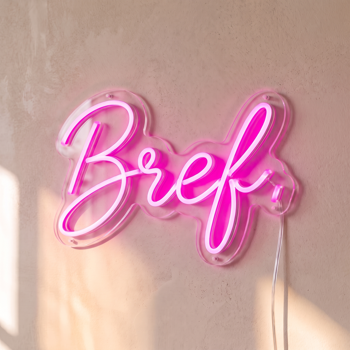 Néon mural « Bref. » rose, gros plan sur fond beige