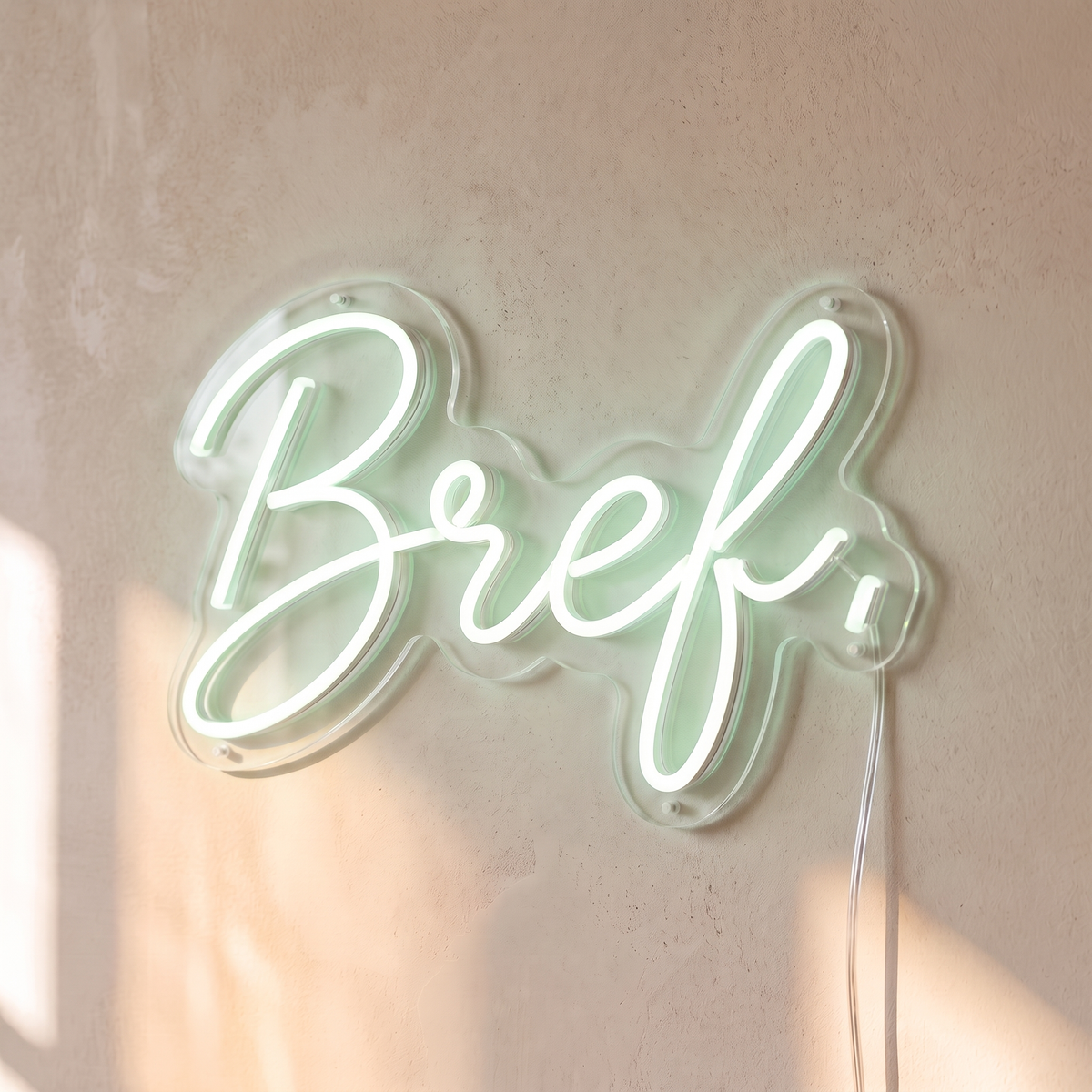 Néon mural « Bref. » blanc froid, gros plan sur fond beige