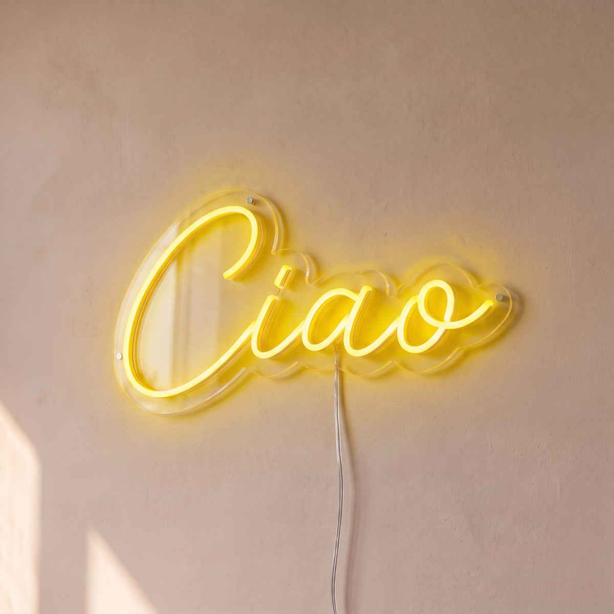 Néon mural « Ciao » jaune, gros plan sur fond beige