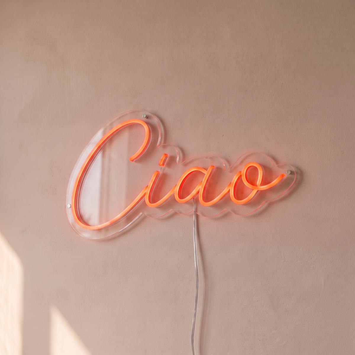 Néon mural « Ciao » rouge orangé, gros plan sur fond beige