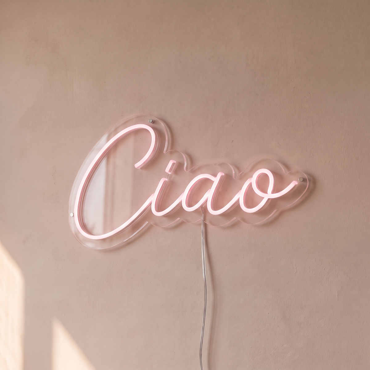 Néon mural « Ciao » rose pâle, gros plan sur fond beige