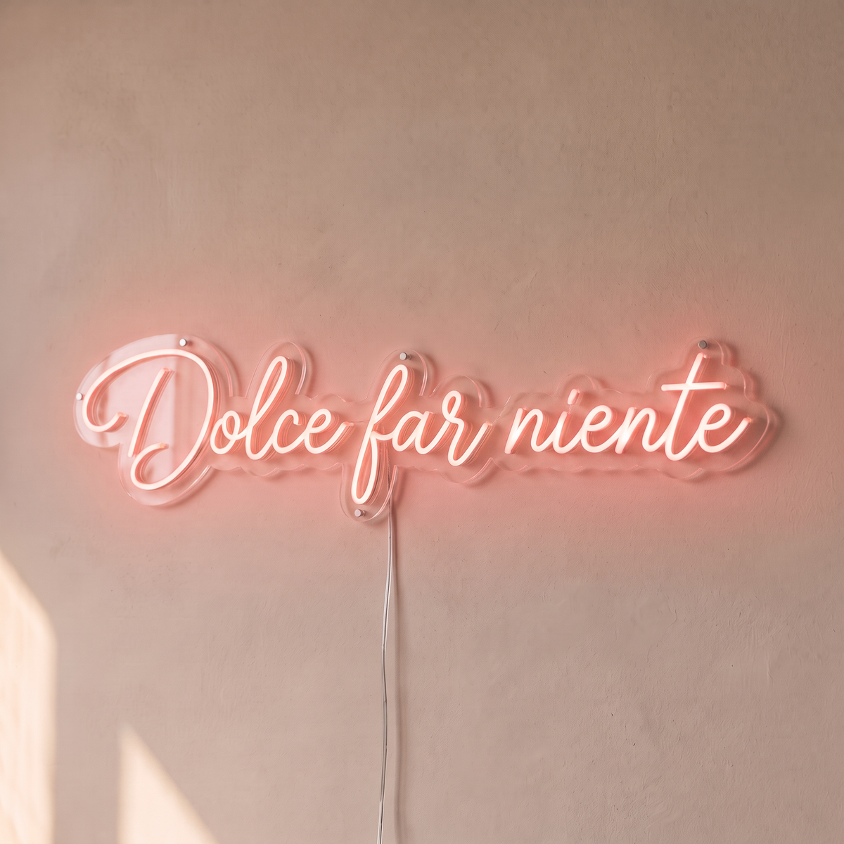 Néon mural « Dolce far niente » rose pâle, gros plan sur fond beige