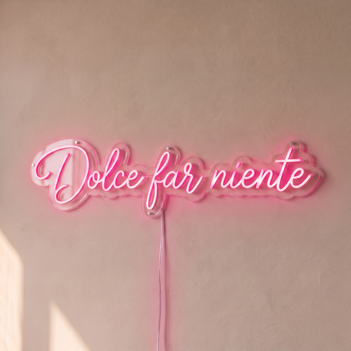 Néon mural « Dolce far niente » rose, gros plan sur fond beige
