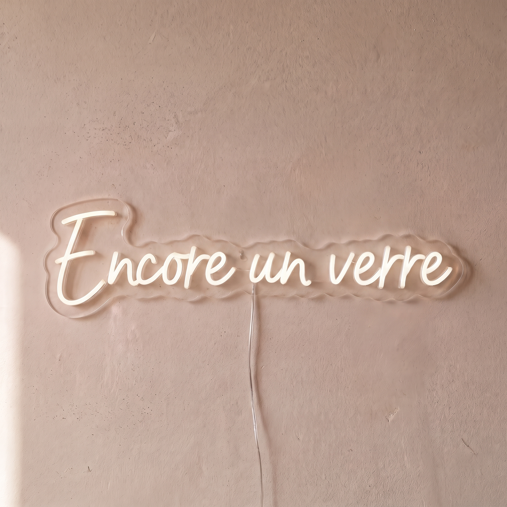 Néon mural « Encore un verre » blanc, gros plan sur fond beige