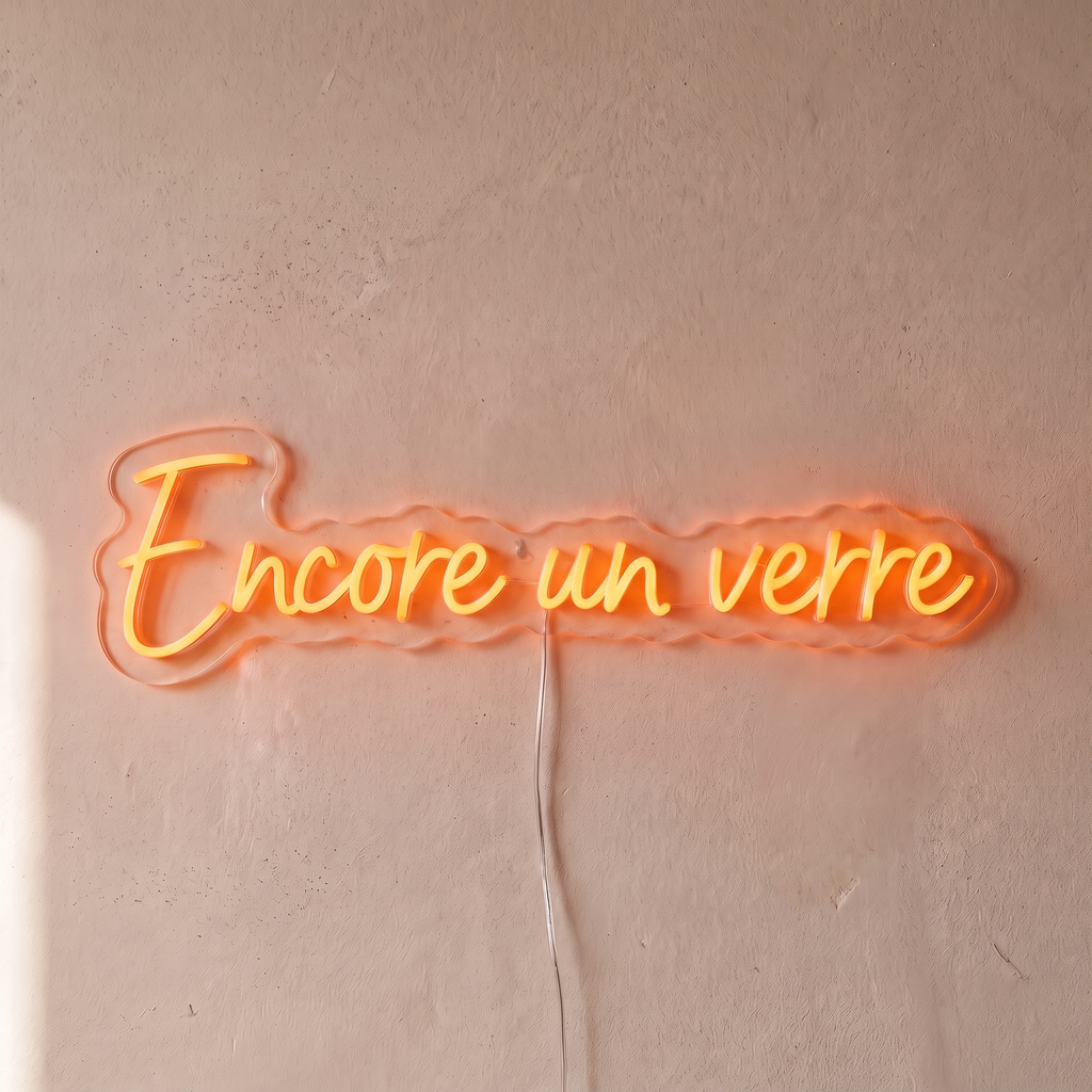 Néon mural « Encore un verre » orange, gros plan sur fond beige