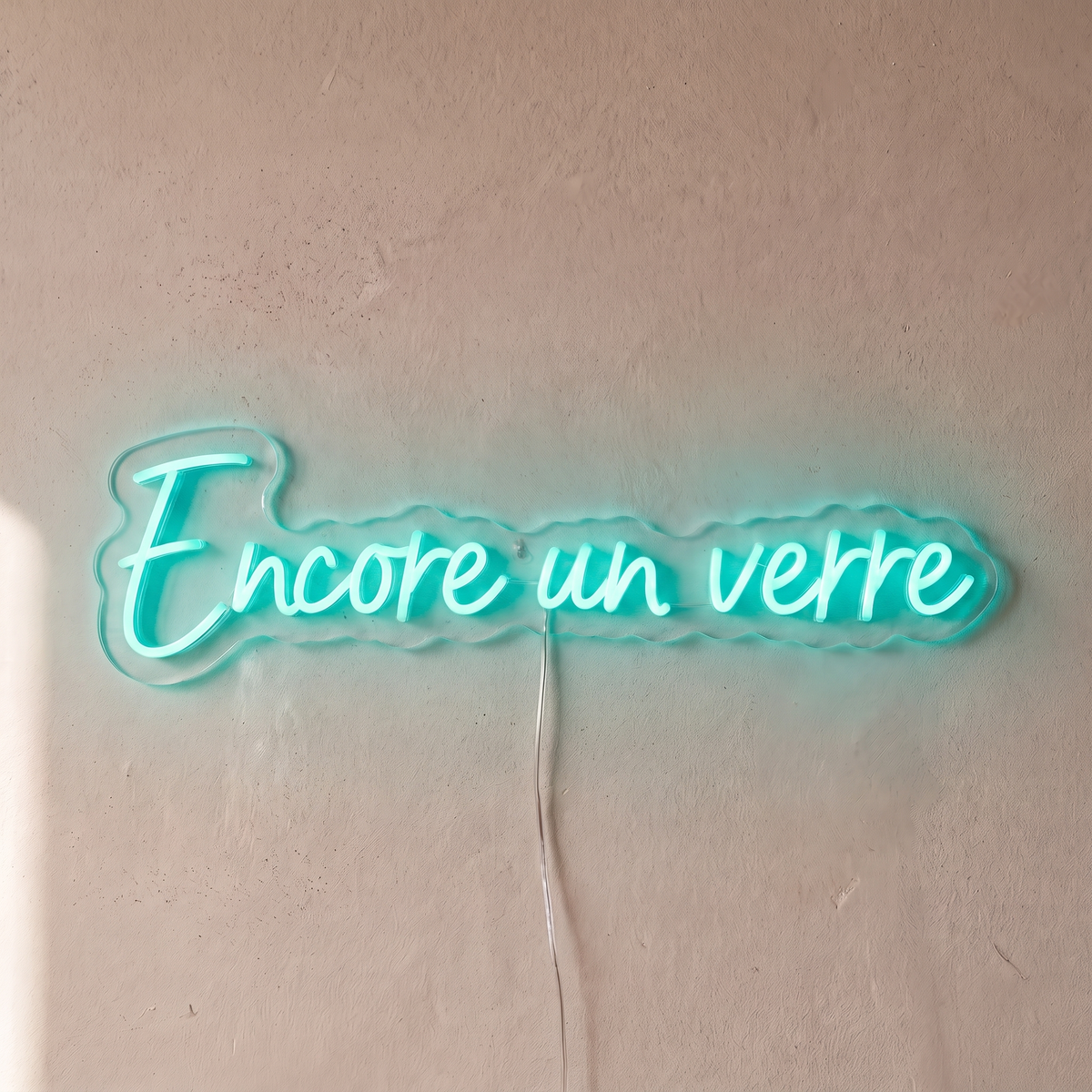 Néon mural « Encore un verre » turquoise, gros plan sur fond beige
