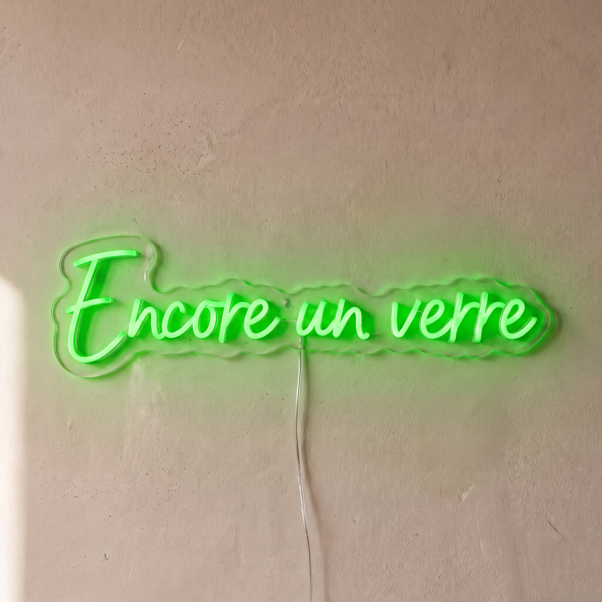 Néon mural « Encore un verre » vert, gros plan sur fond beige