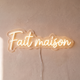 Néon mural « Fait maison » blanc chaud, gros plan sur fond beige