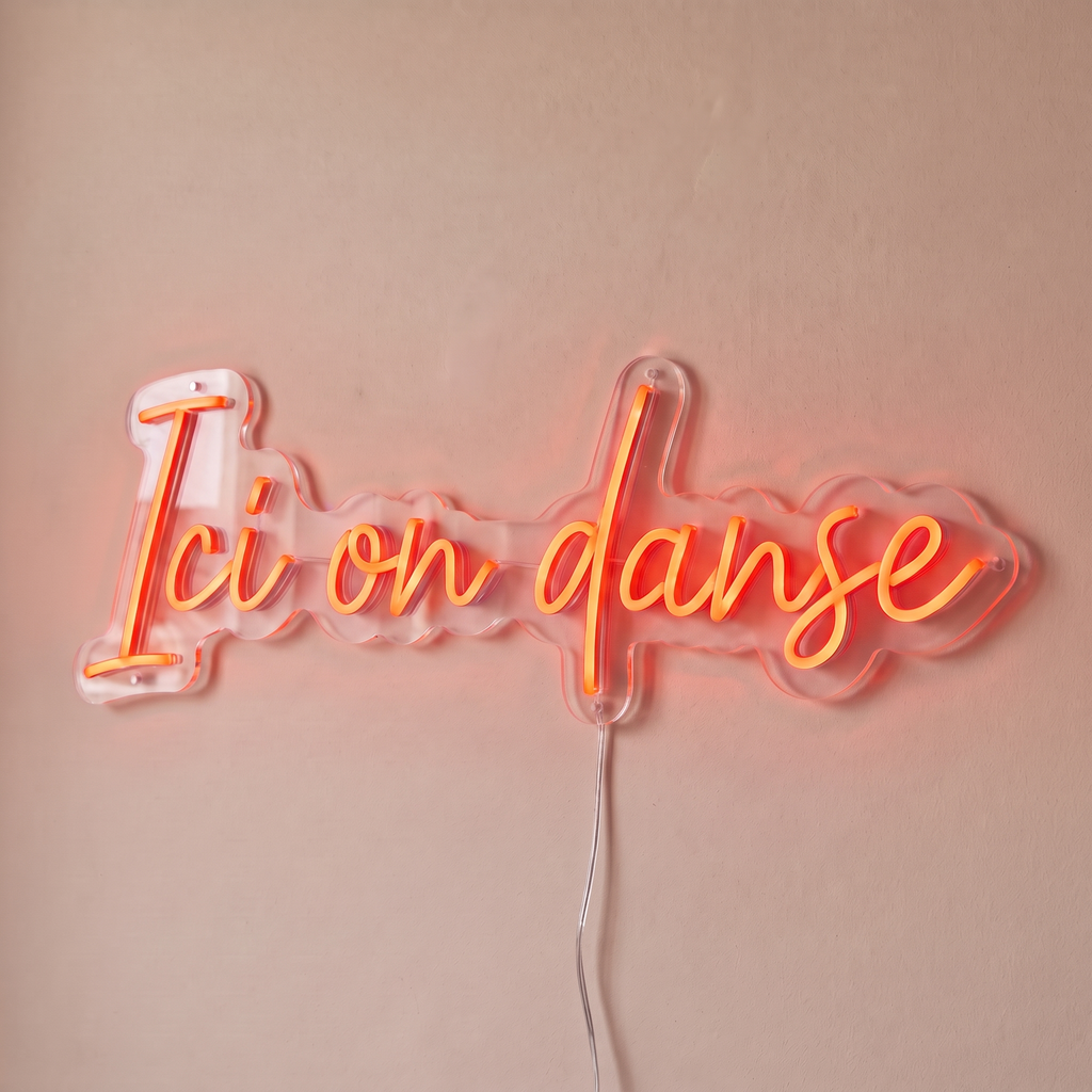 Néon mural « Ici on danse » rouge orangé, gros plan sur fond beige
