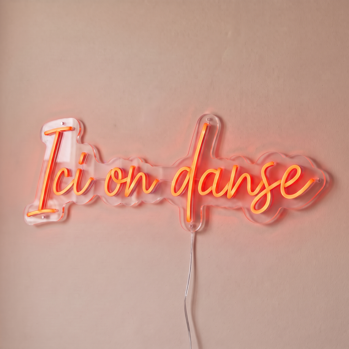 Néon mural « Ici on danse » rouge orangé, gros plan sur fond beige
