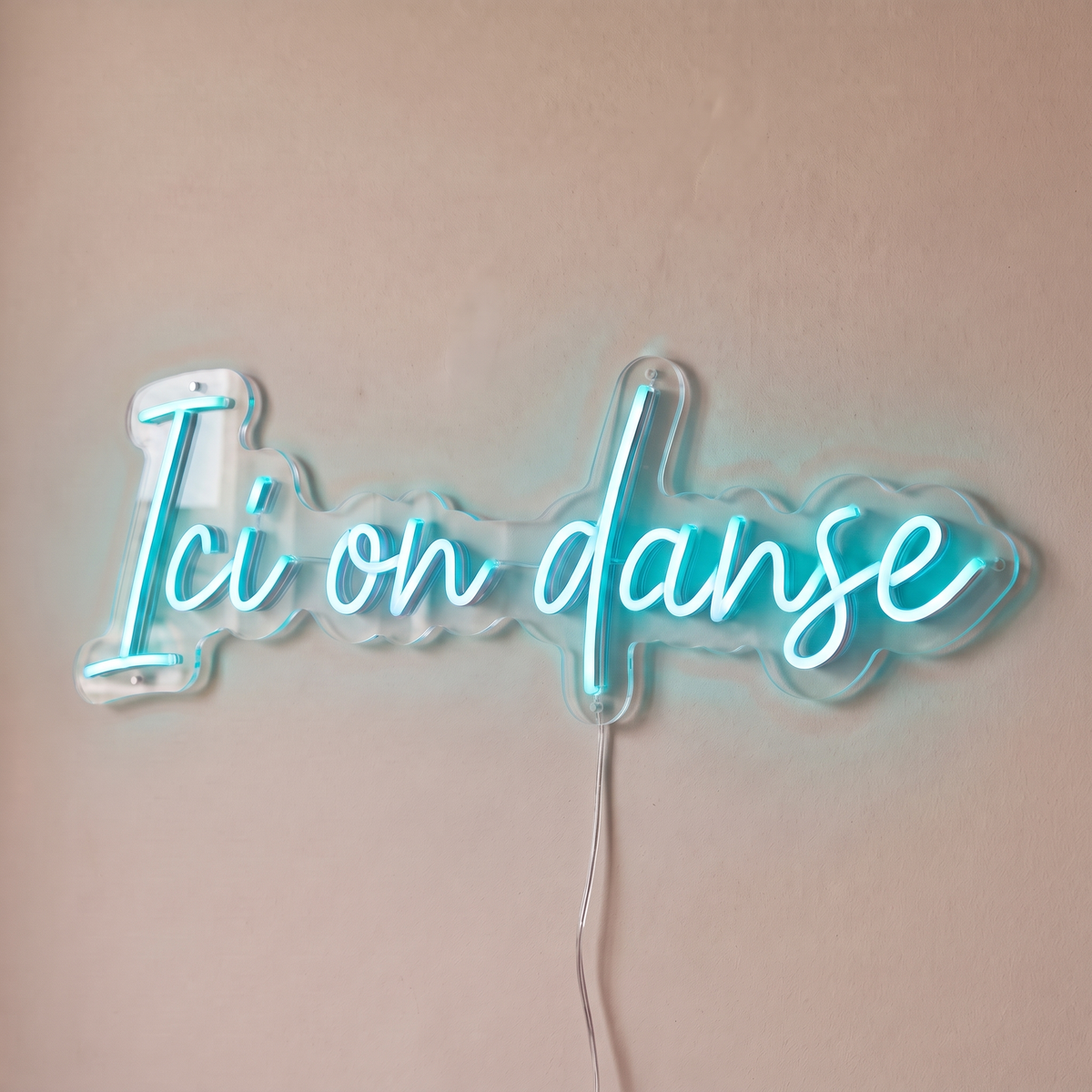 Néon mural « Ici on danse » turquoise, gros plan sur fond beige
