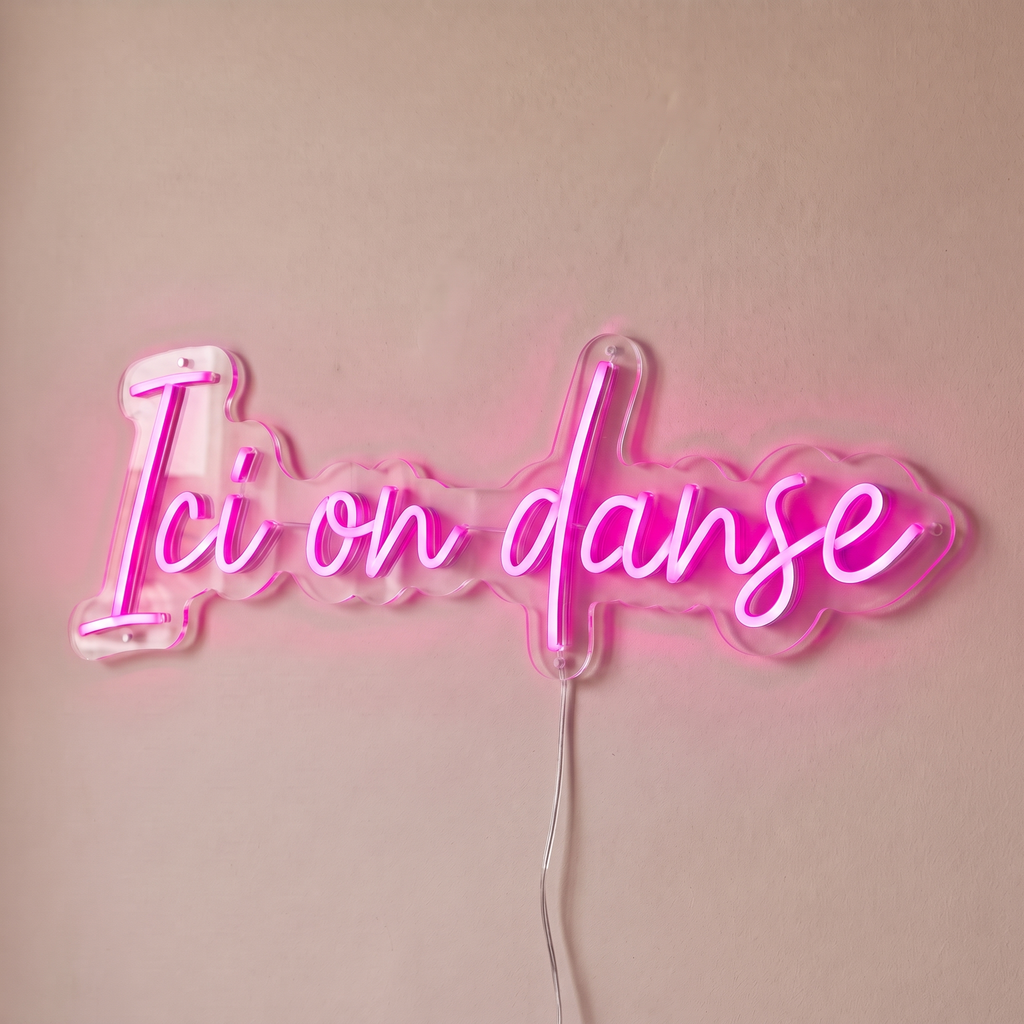 Néon mural « Ici on danse » rose, gros plan sur fond beige