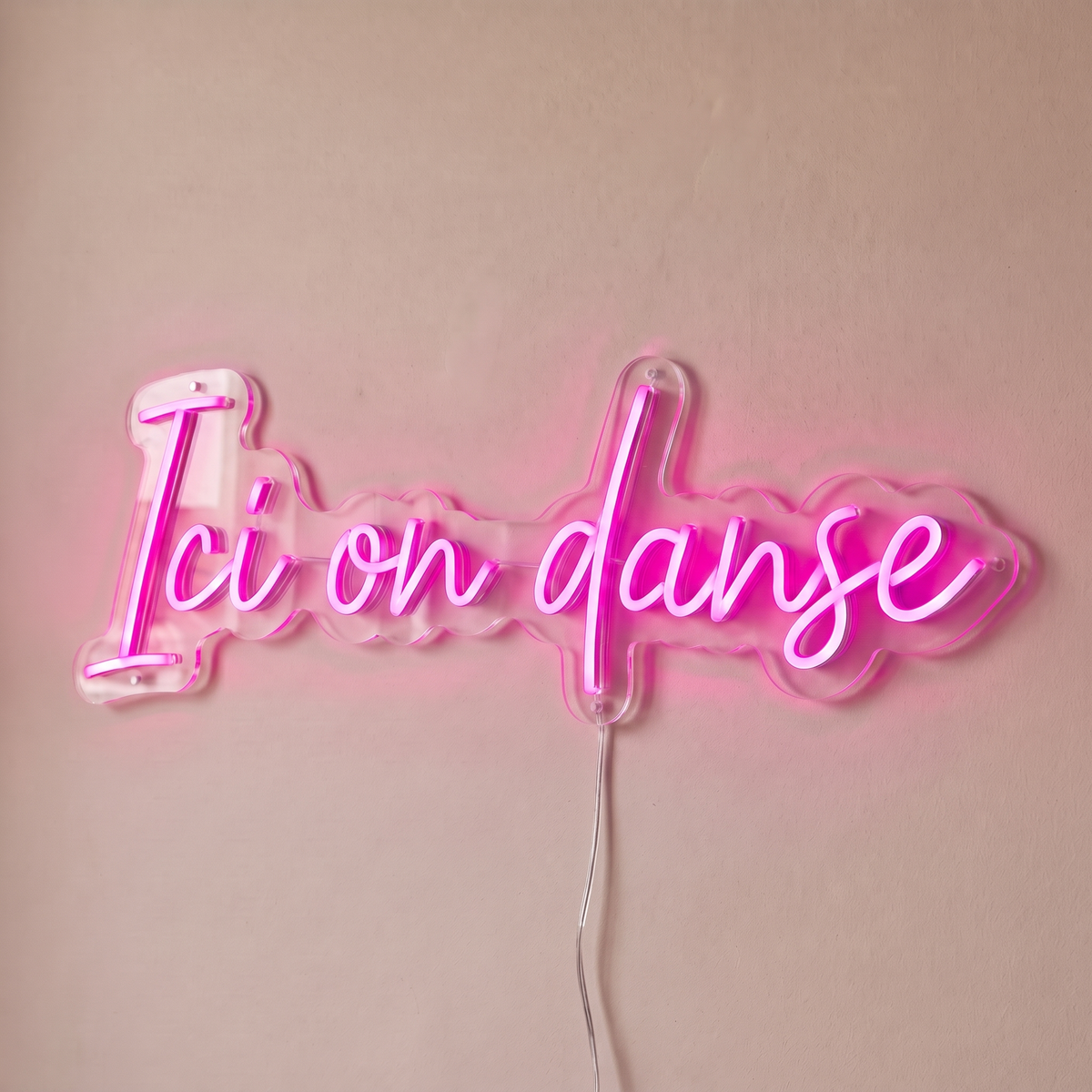 Néon mural « Ici on danse » rose, gros plan sur fond beige