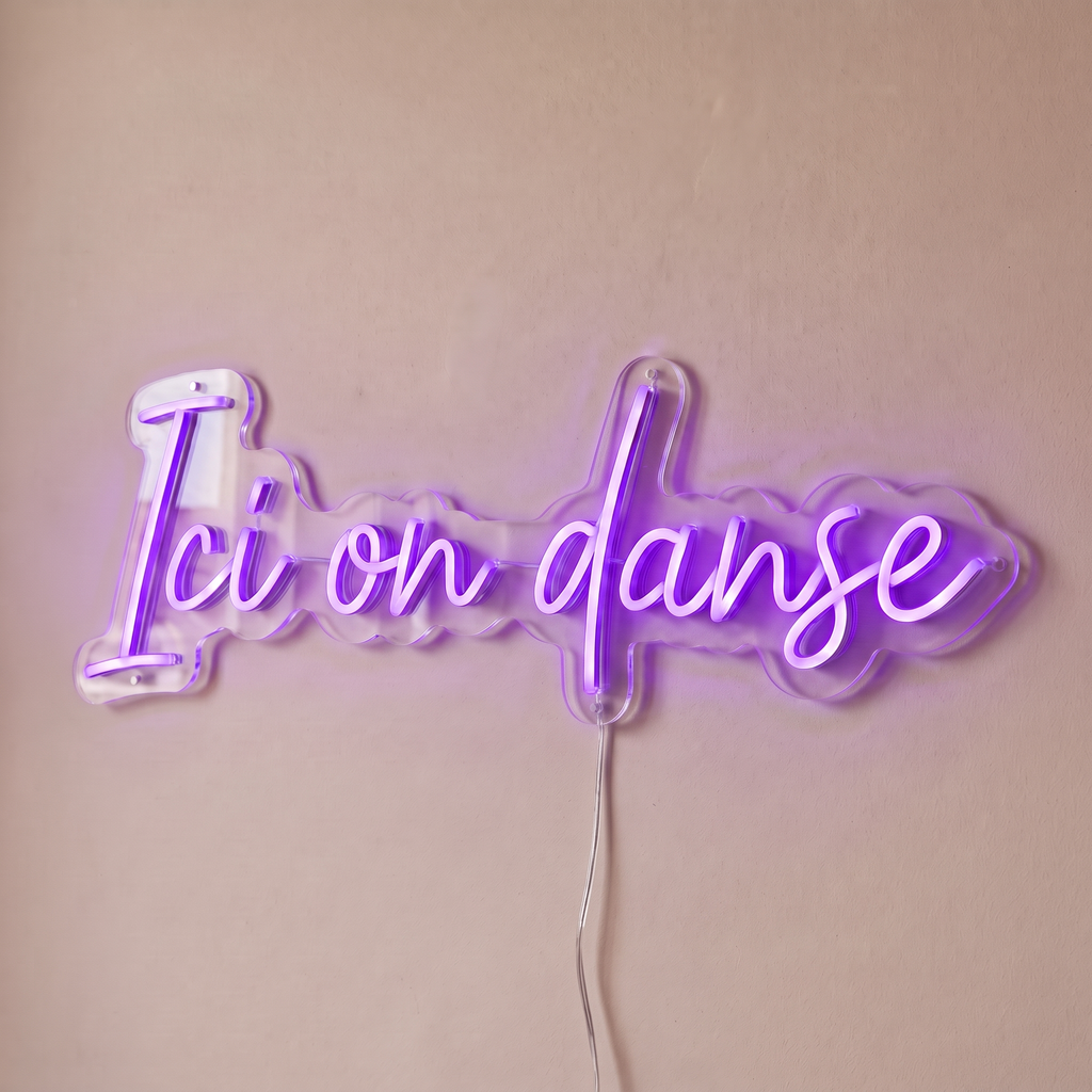 Néon mural « Ici on danse » violet, gros plan sur fond beige