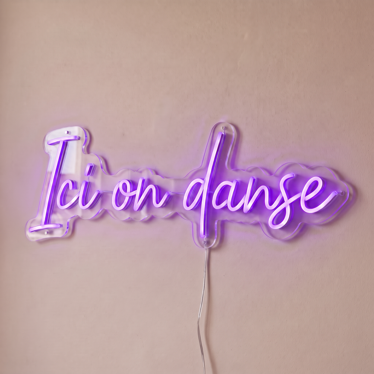 Néon mural « Ici on danse » violet, gros plan sur fond beige