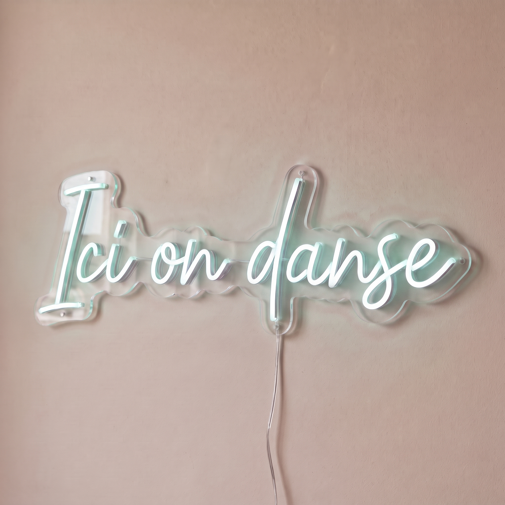 Néon mural « Ici on danse » blanc froid, gros plan sur fond beige