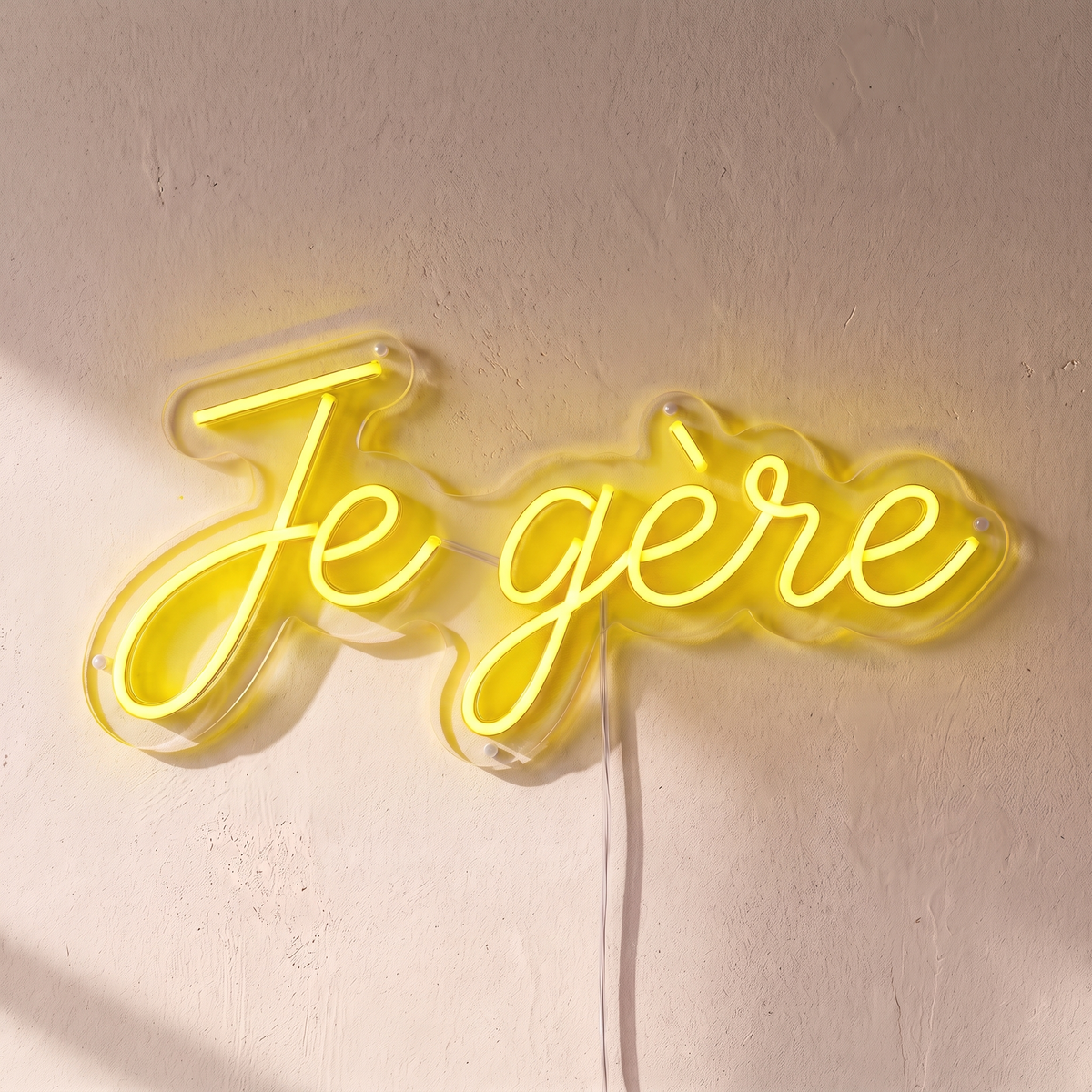 Néon mural « Je gère » jaune, gros plan sur fond beige