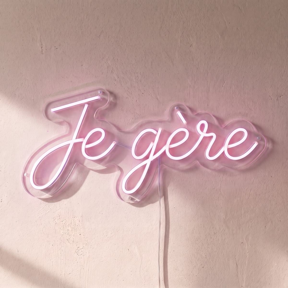 Néon mural « Je gère » rose pâle, gros plan sur fond beige