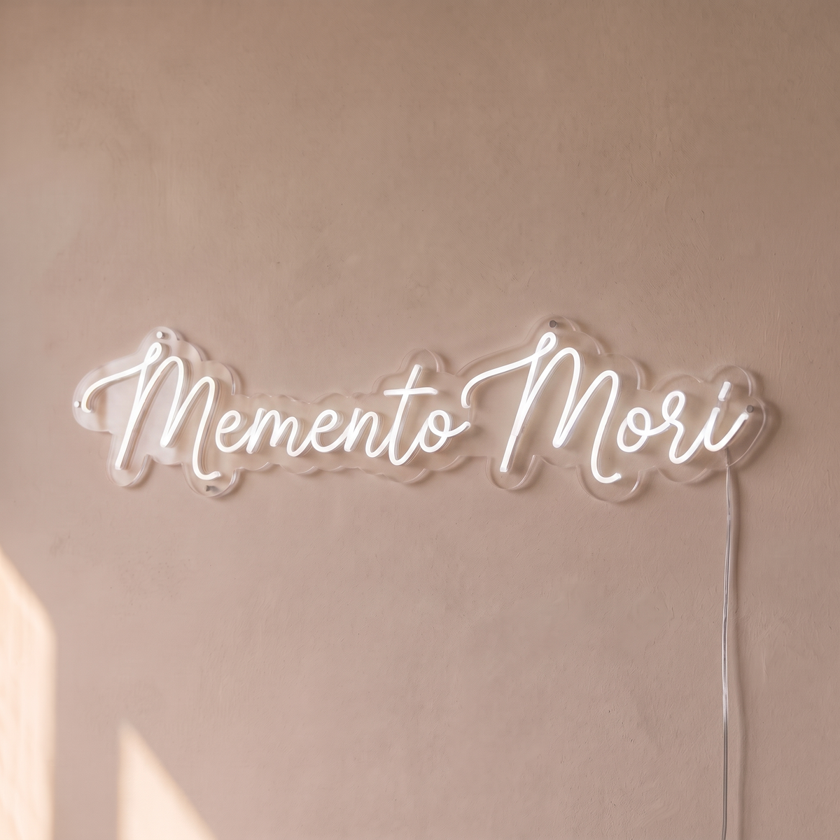 Néon mural « Memento Mori » blanc, gros plan sur fond beige