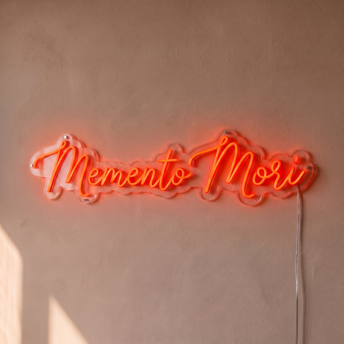 Néon mural « Memento Mori » rouge orangé, gros plan sur fond beige
