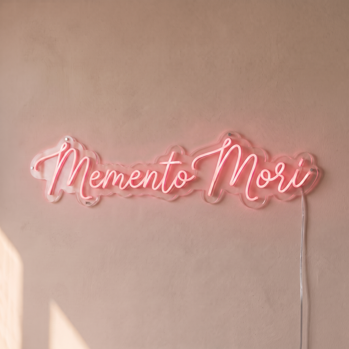 Néon mural « Memento Mori » rose pâle, gros plan sur fond beige