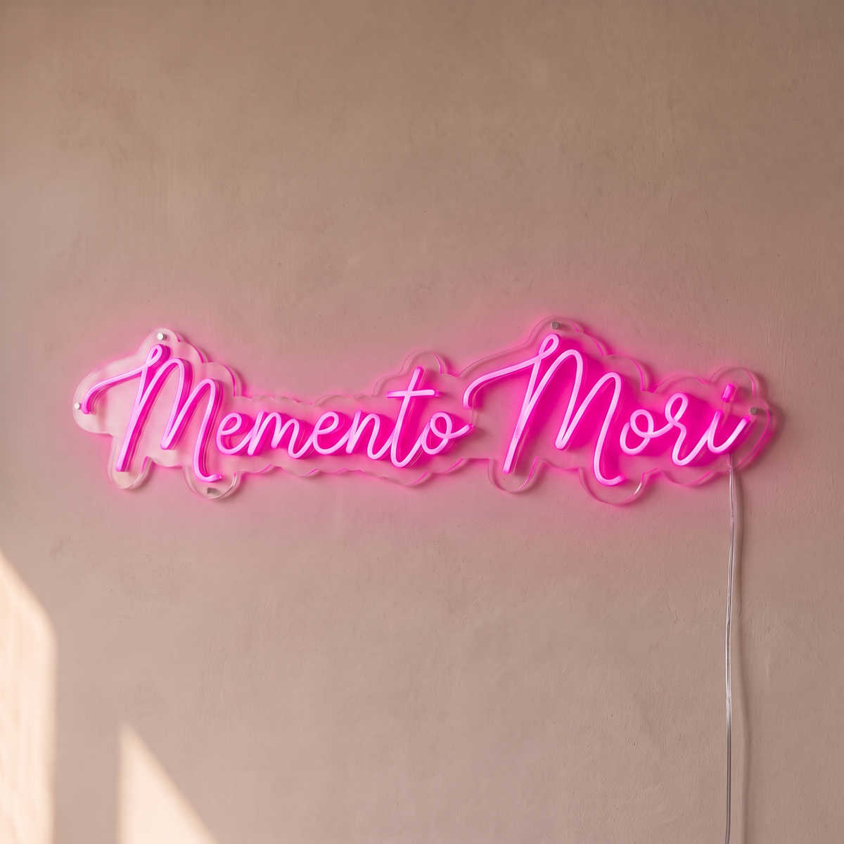 Néon mural « Memento Mori » rose, gros plan sur fond beige