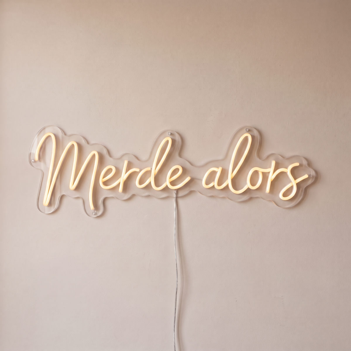 Néon mural « Merde alors » blanc chaud, gros plan sur fond beige