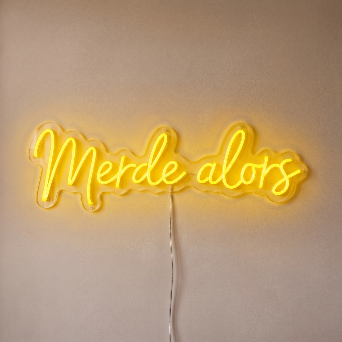 Néon mural « Merde alors » jaune, gros plan sur fond beige