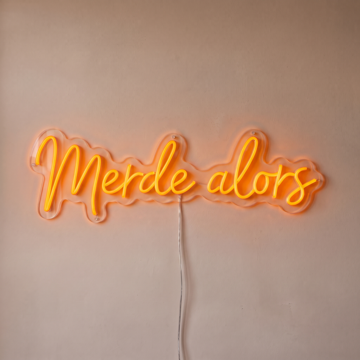Néon mural « Merde alors » orange, gros plan sur fond beige