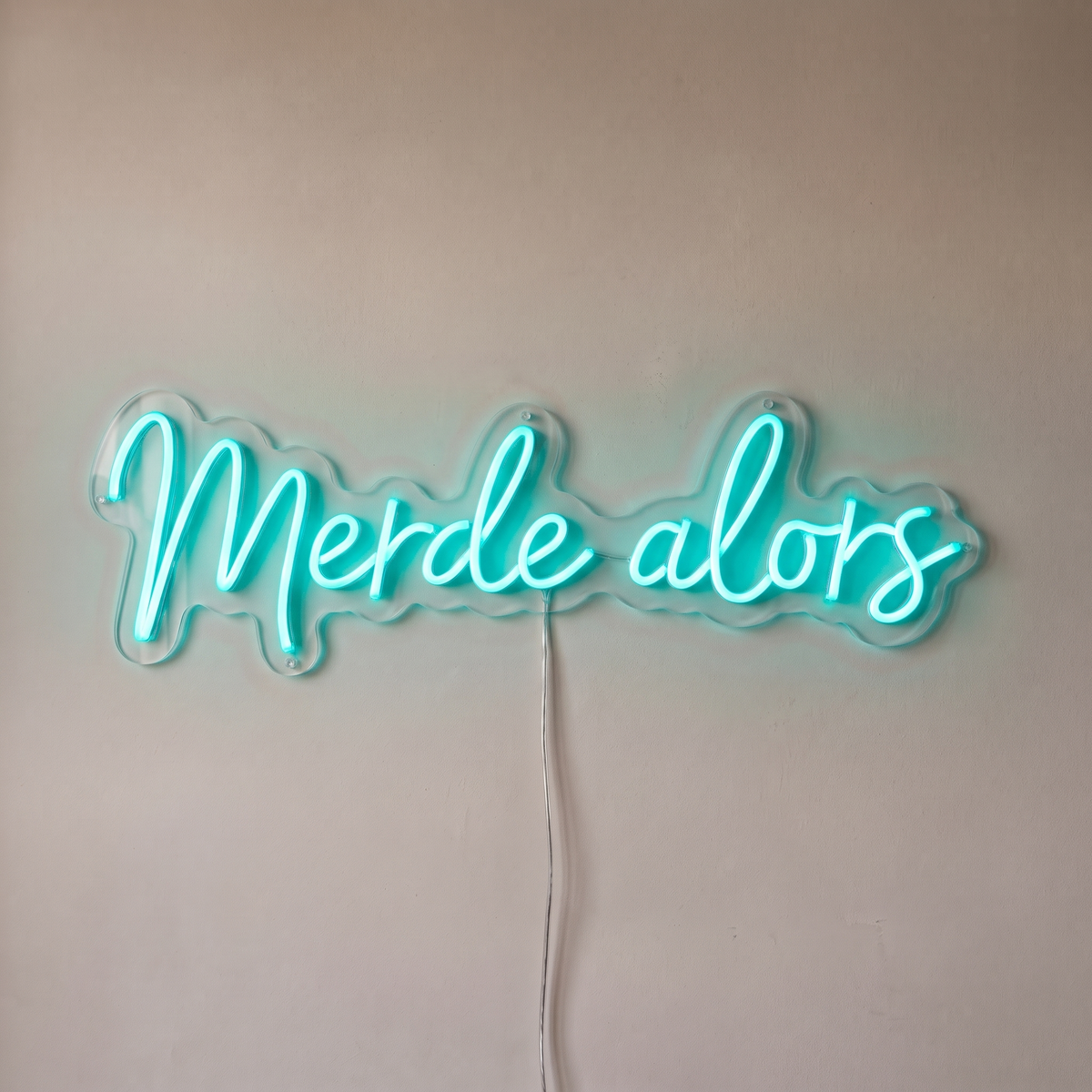 Néon mural « Merde alors » turquoise, gros plan sur fond beige